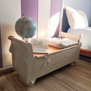 Ancien berceau en noyer transformé en coffre de rangement couleur lin et vert sauge avec couvercle amovible en pin vernis. Pieds boule pour une stabilité.